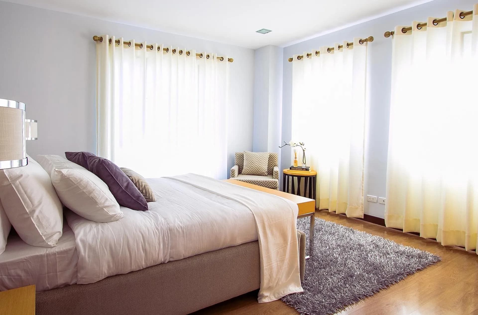 Bedroom with a made bed, white linen and sheer curtains