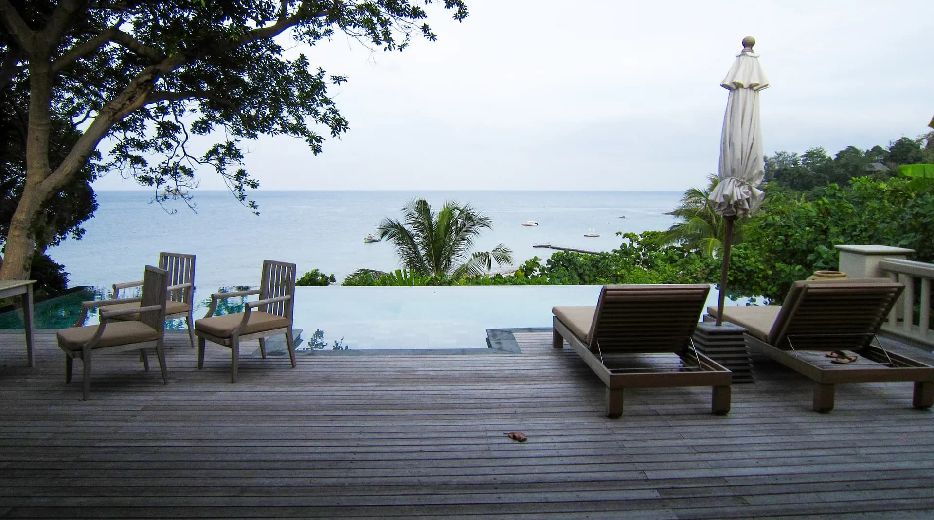 Wooden deck with sun loungers and a pool overlooking the sea