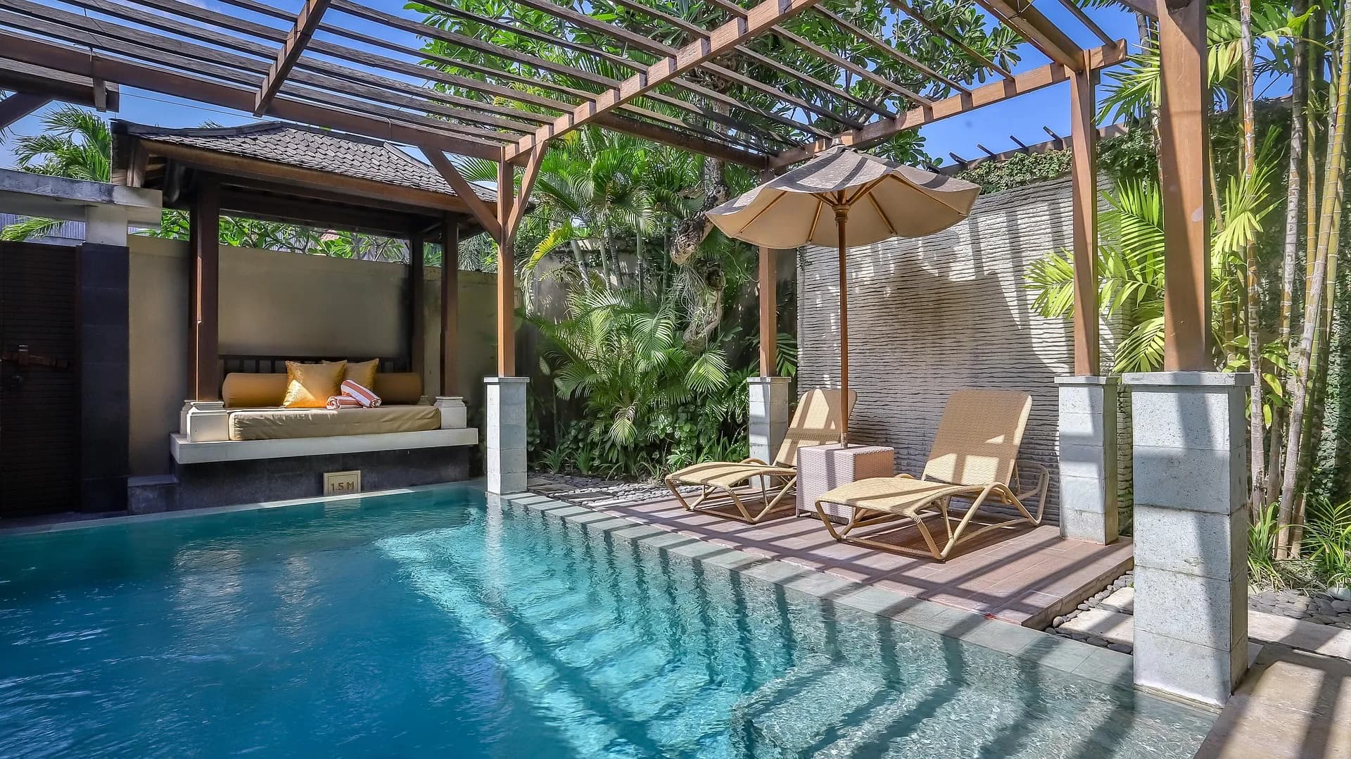 Swimming pool beside a wooden pergola with a daybed and sun loungers